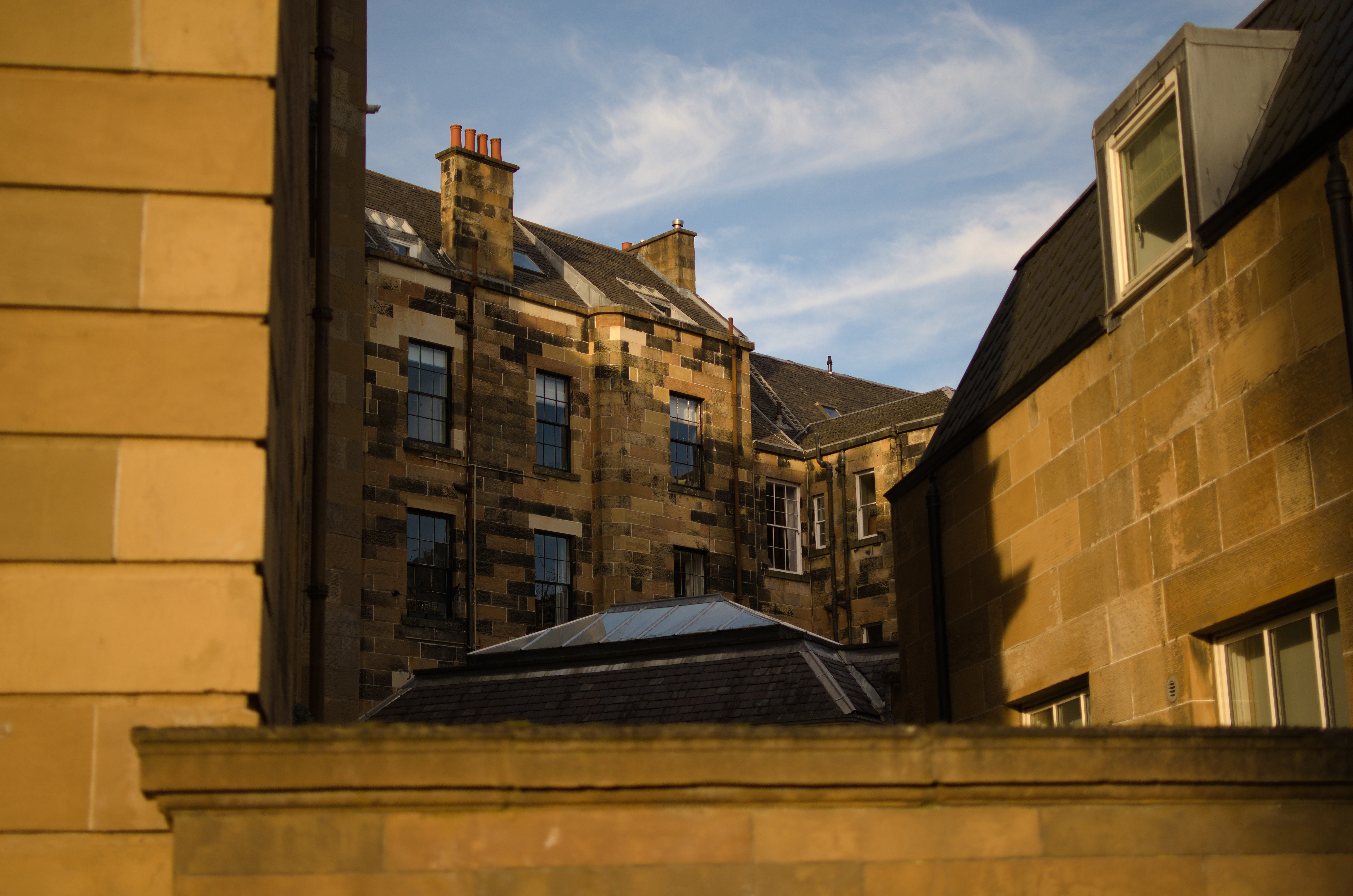 A
		sandstone tenement in the evening, wispy blue skies in the
		background.